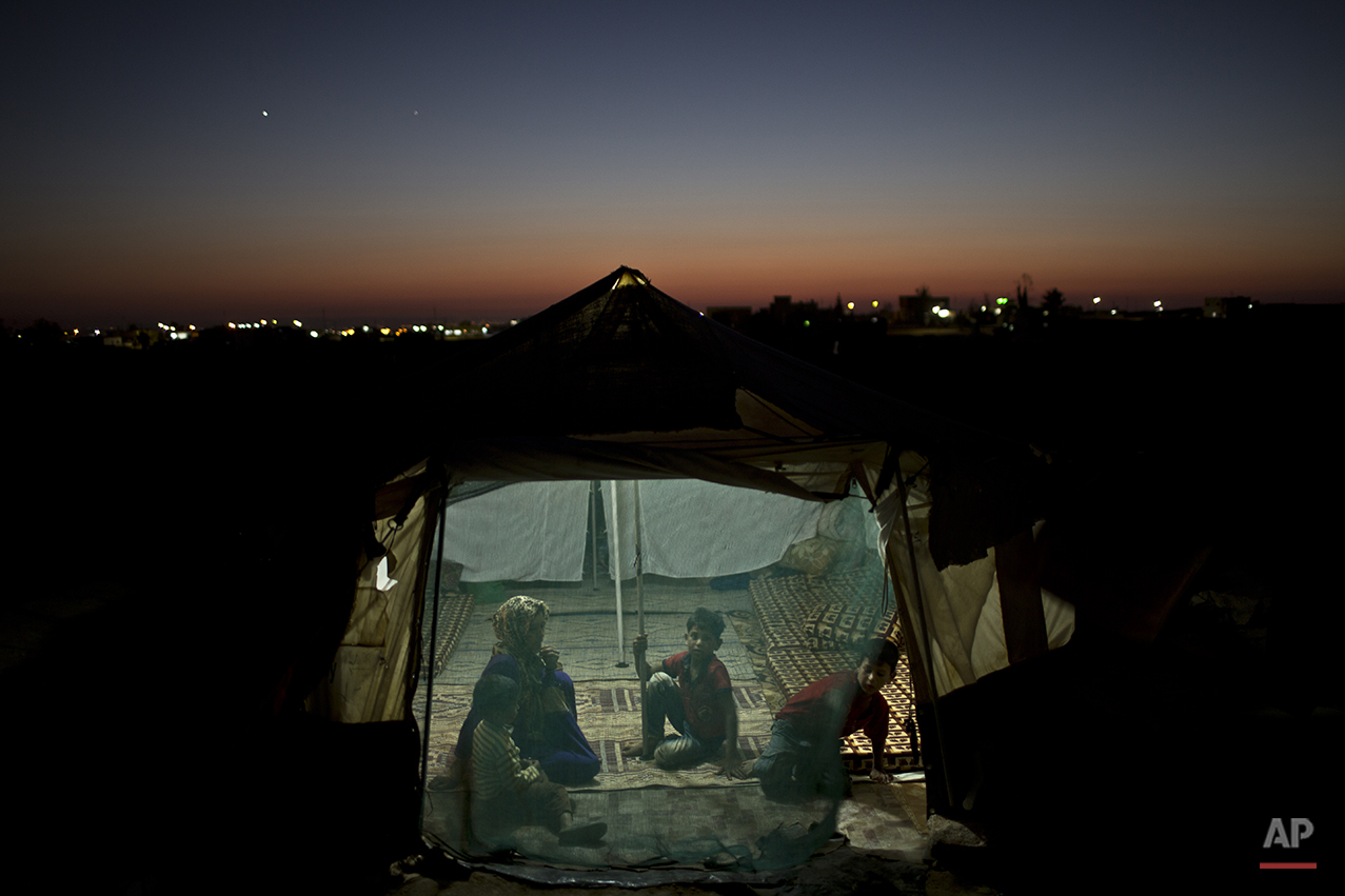  In this Wednesday, July 22, 2015 photo, Syrian refugee Eidah Hassoun, 36, sits with her children inside their tent at an informal tented settlement near the Syrian border on the outskirts of Mafraq, Jordan. More than 10,000 children have died in Syr