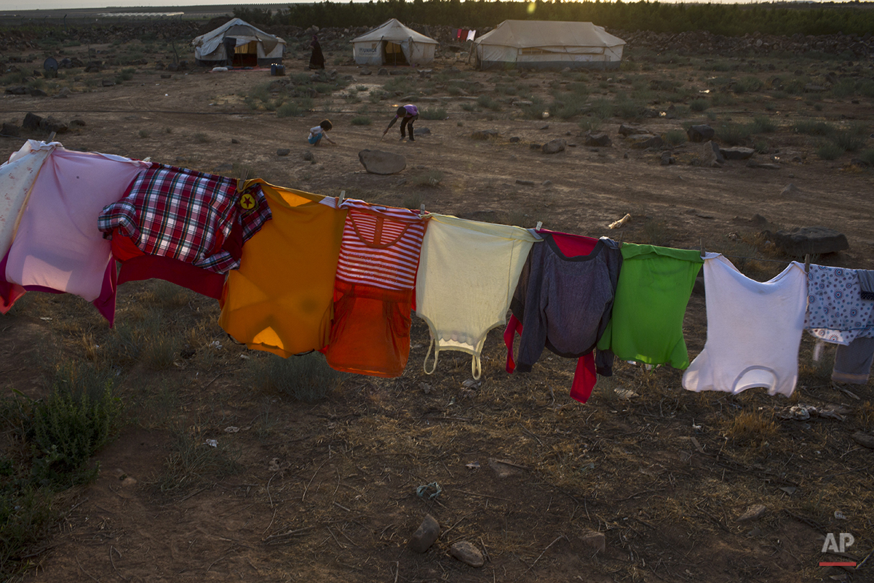  In this Monday, July 27, 2015 photo, clothes of Syrian refugee children hang out to dry outside a tent at an informal settlement near the Syrian border on the outskirts of Mafraq, Jordan. More than 10,000 children have died in Syria's four-year conf