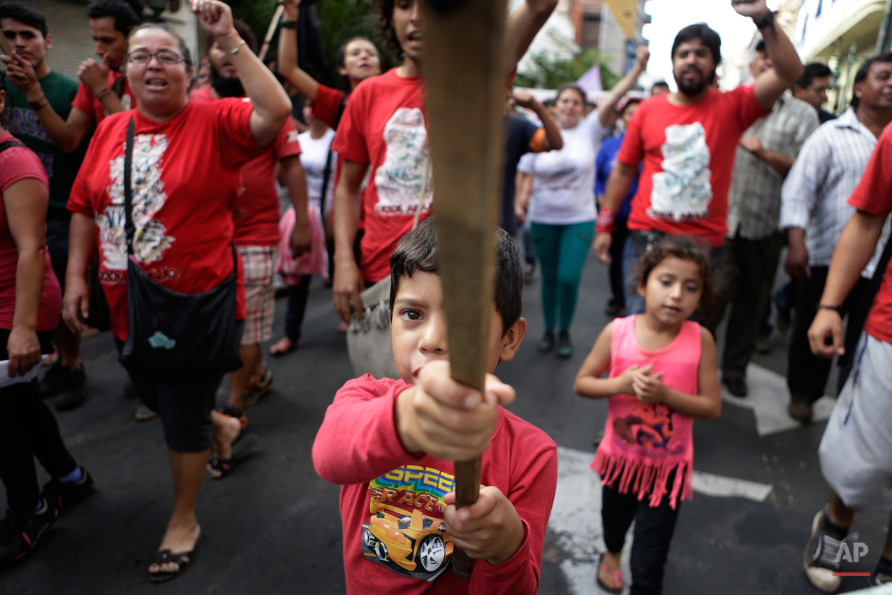  Kevin, 8, waves a banner as workers shout slogans against Paraguay's government during a march marking May Day celebrations in Asuncion's downtown, Paraguay, Friday, May 1, 2015. (AP Photo/Jorge Saenz) 