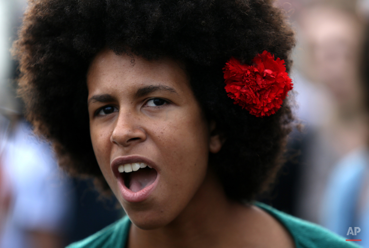  A woman, wearing a red carnation in her hair, sings a protest song during a march marking the international May Day, in Lisbon, Friday, May 1, 2015. The red carnation is the symbol of the revolution that restored the democracy in Portugal in 1974. (