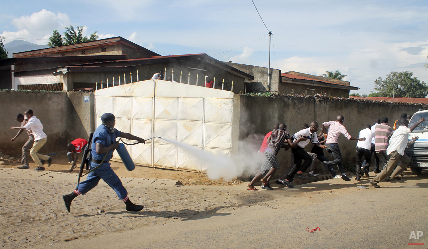  A Burundian riot policeman sprays tear gas on opposition protesters in the capital Bujumbura, Burundi Monday, April 27, 2015. Street protests continued Monday in Burundi as anger mounts over the ruling party's decision on Saturday to nominate Presid