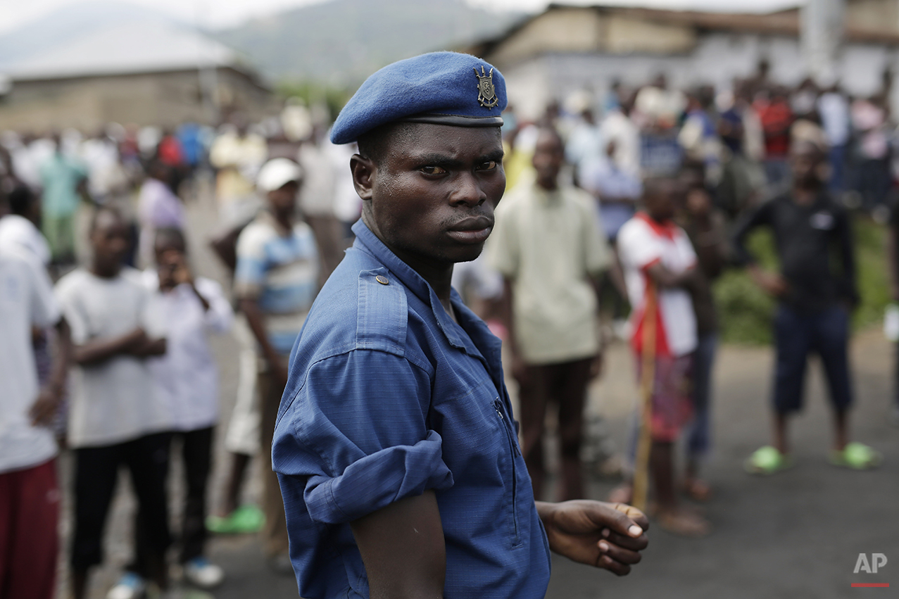  A Burundi police officer stands in front of a group of protesters in Bujumbura, Burundi, Wednesday, April 29, 2015. Anti-government street demonstrations continued for a fourth day after six people died in protests against the move by President Pier