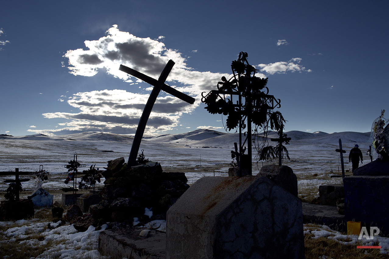  In this July 9, 2016 photo, a cross stands in a snow covered cemetery in San Antonio de Putina in the Puno region of Peru, where people raise alpacas and sheep for their wool. "Every year with the winter freezes and cold temperatures the plants and 
