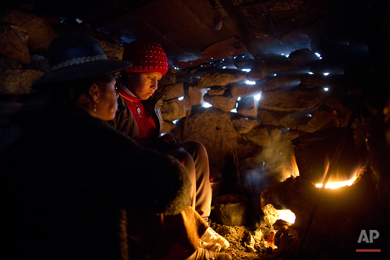  In this July 9, 2016 photo, Rosa Carcabusto and her daughter Maria Luque warm themselves by the fire where they cook soup made of wheat and dried potatoes in San Antonio de Putina in the Puno region of Peru. In stark contrast to the high prices char