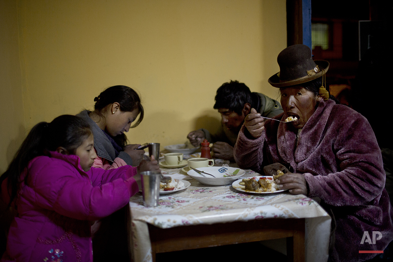  In this July 11, 2016 photo, villagers eat dinner at the town's only general store in San Antonio de Putina in the Puno region of Peru. Peru is the world's largest producer of alpaca wool, and the rural hamlets in this area is where the white-furred
