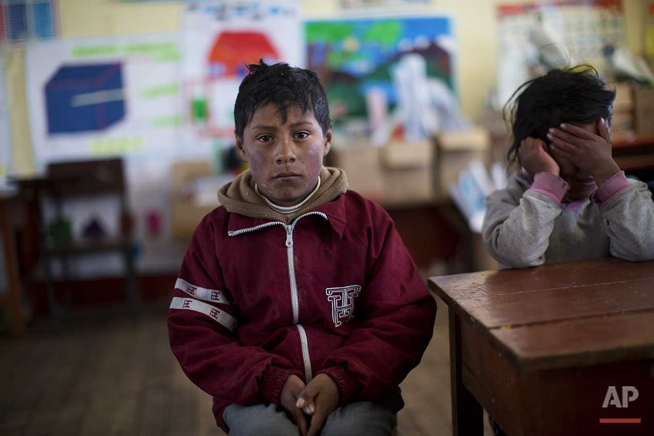  In this July 9, 2016 photo, a student waits for class to start at his public school in San Antonio de Putina in the Puno region of Peru. Due to the recent sub-freezing temperatures, the start of the school day has been delayed to 9am. (AP Photo/Rodr