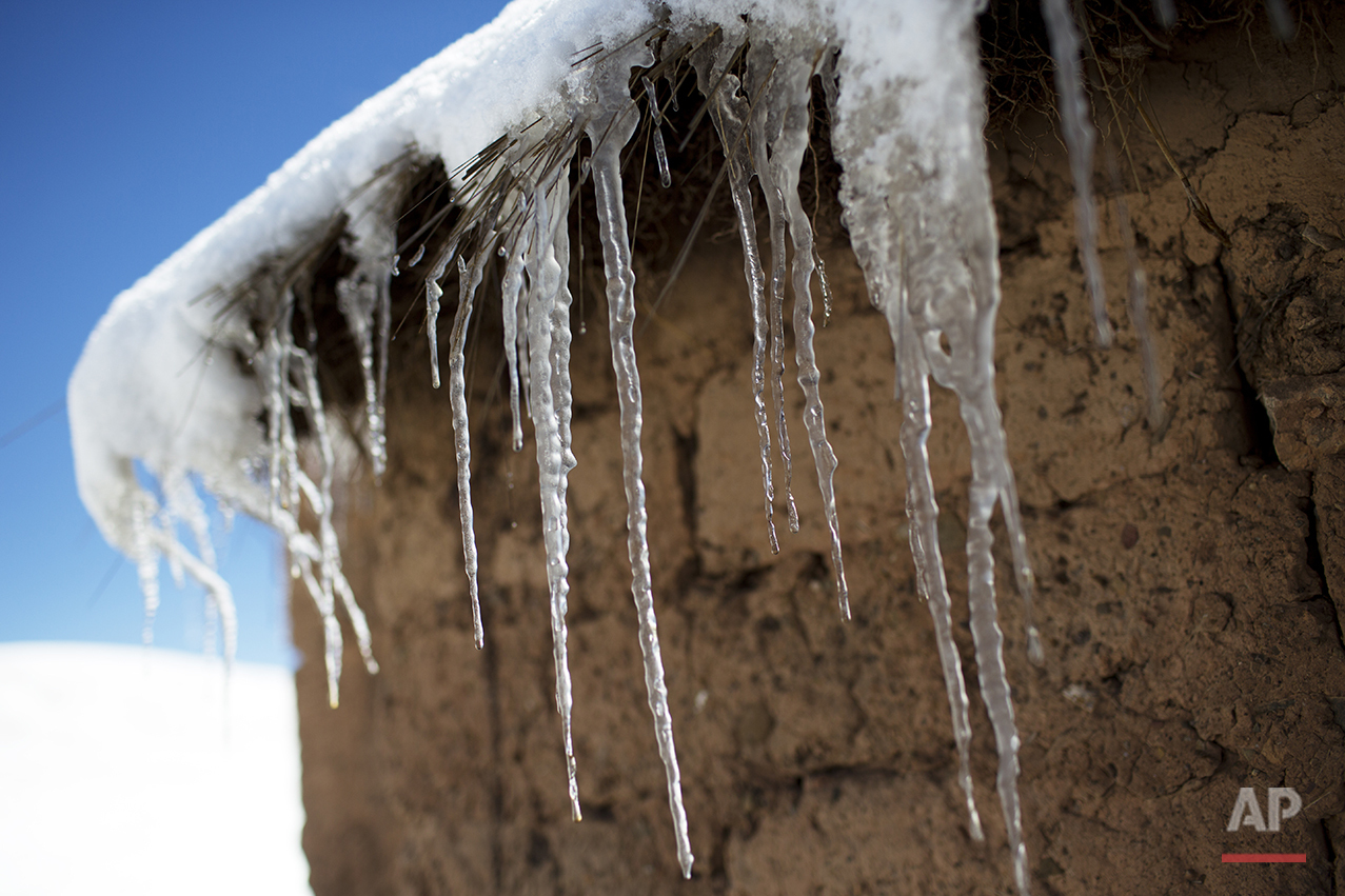  In this July 8, 2016 photo, icicles hang from the roof of an adobe home in San Antonio de Putina in the Puno region of Peru, where farmers raise alpacas and sheep for their wool. Every winter freeze destroys the tough grasslands the animals feed on 