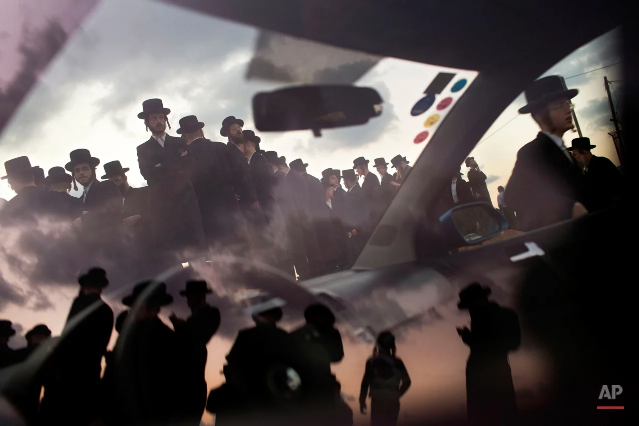  Ultra-Orthodox Jews of the Hassidic sect Vizhnitz reflect on a car window as they gather on a hill overlooking the Mediterranean sea as they participate in a Tashlich ceremony in Herzeliya, Israel, Thursday, Oct. 2, 2014. Tashlich, which means "to c