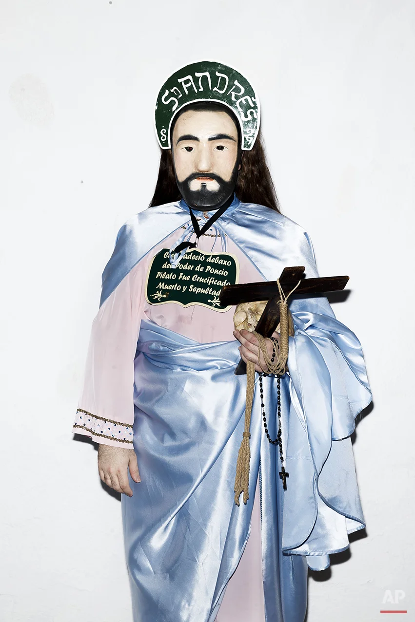 A penitent poses for a picture dressed with typical Apostle dress, holding a Cross in one hand and an ancient human skull from a unidentified person, before the Holy Week procession by the 'Nuestro Padre Jesus Nazareno and Nuestra Señora de la Piedad' brotherhood in Iznajar, Spain, Friday, April 3, 2015. Among the characters taking part in the procession are the “Brotherhood of the Apostles,” represented, as the name suggests, by 12 townsfolk who don a distinctive mask, dress up in robes, carry a rosary and process behind an urn carved in the shape of the “Dead Christ.” Each apostle carries a human skull, a black cross and words taken from the Roman Catholic credo. (AP Photo/Daniel Ochoa de Olza)