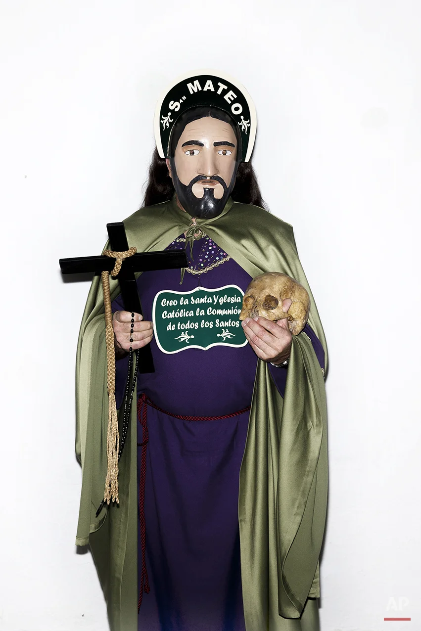 A penitent poses for a picture dressed with typical Apostle dress, holding a Cross in one hand and an ancient human skull from a unidentified person, before the Holy Week procession by the 'Nuestro Padre Jesus Nazareno and Nuestra Señora de la Piedad' brotherhood in Iznajar, Spain, Friday, April 3, 2015. Among the characters taking part in the procession are the “Brotherhood of the Apostles,” represented, as the name suggests, by 12 townsfolk who don a distinctive mask, dress up in robes, carry a rosary and process behind an urn carved in the shape of the “Dead Christ.” Each apostle carries a human skull, a black cross and words taken from the Roman Catholic credo. (AP Photo/Daniel Ochoa de Olza)