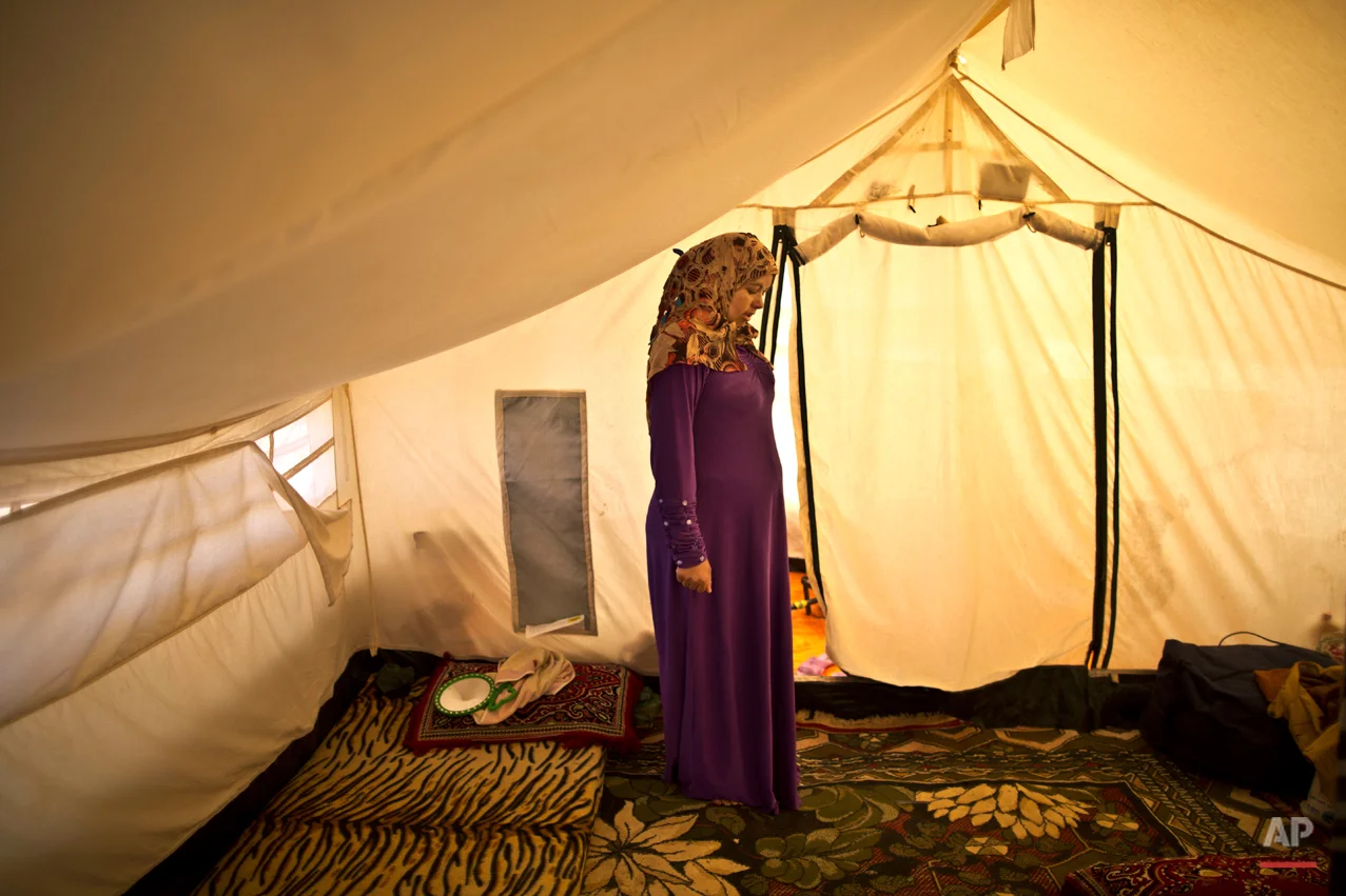  In this Tuesday, March 17, 2015 photo, Syrian refugee Adala Ismail, 32, who is six months pregnant, poses for a portrait inside her tent at an informal settlement near the Syrian border, on the outskirts of Mafraq, Jordan. Expectant mothers in these