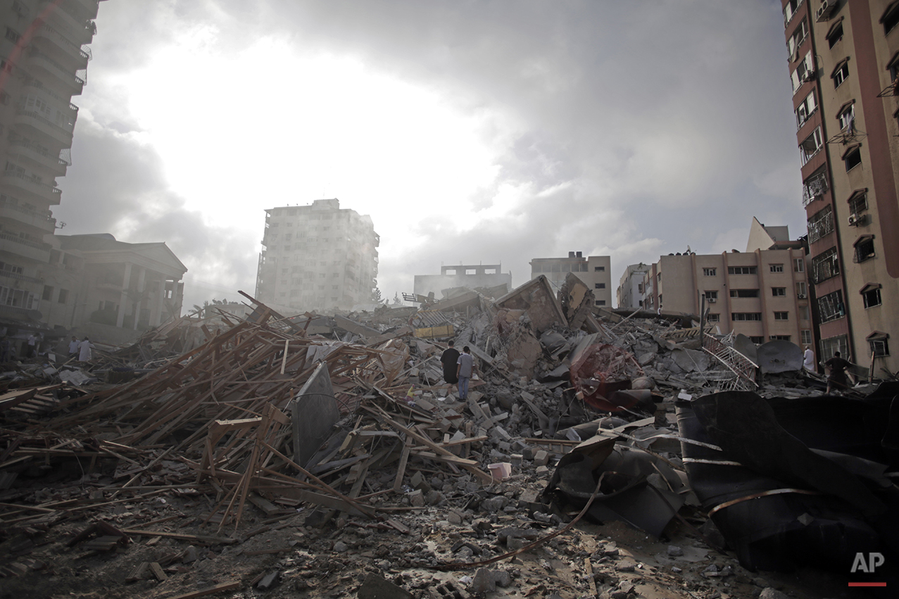  Palestinians inspect the rubble of the Al-Zafer apartment tower following Israeli airstrikes Saturday that collapsed the 12-story building, in Gaza City, Sunday, Aug. 24, 2014. The Israeli army said the Gaza City apartment tower was targeted because