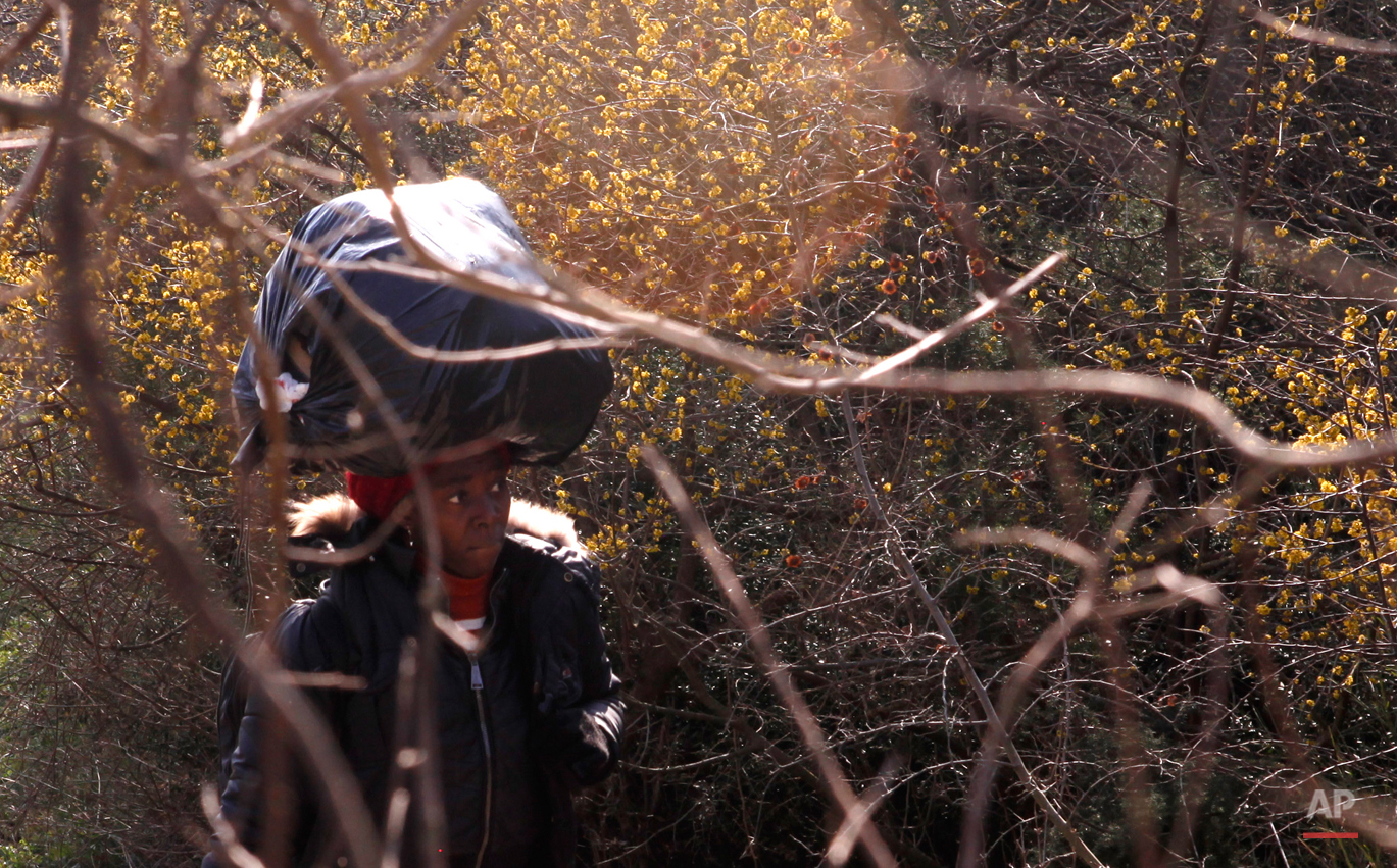  In this Saturday, Feb. 28, 2015 photo Sandrine from Cameroon carries her belongings on her head on her way to the Greek-Macedonian border near the town of Polikastro, Greece.  The tide of hopeful migrants pours through the vulnerable 'back-door' cou