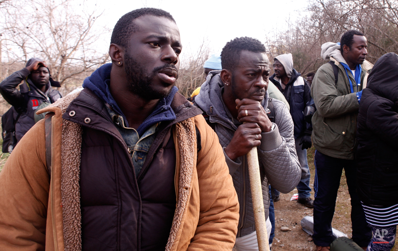  In this Saturday, Feb. 28, 2015 photo Jean Leblanc, left, and Antoine Sannick of Ivory Coast rest on their way to the Greek-Macedonian border near the town of Polikastro, Greece.  The tide of hopeful migrants pours through the vulnerable 'back-door'