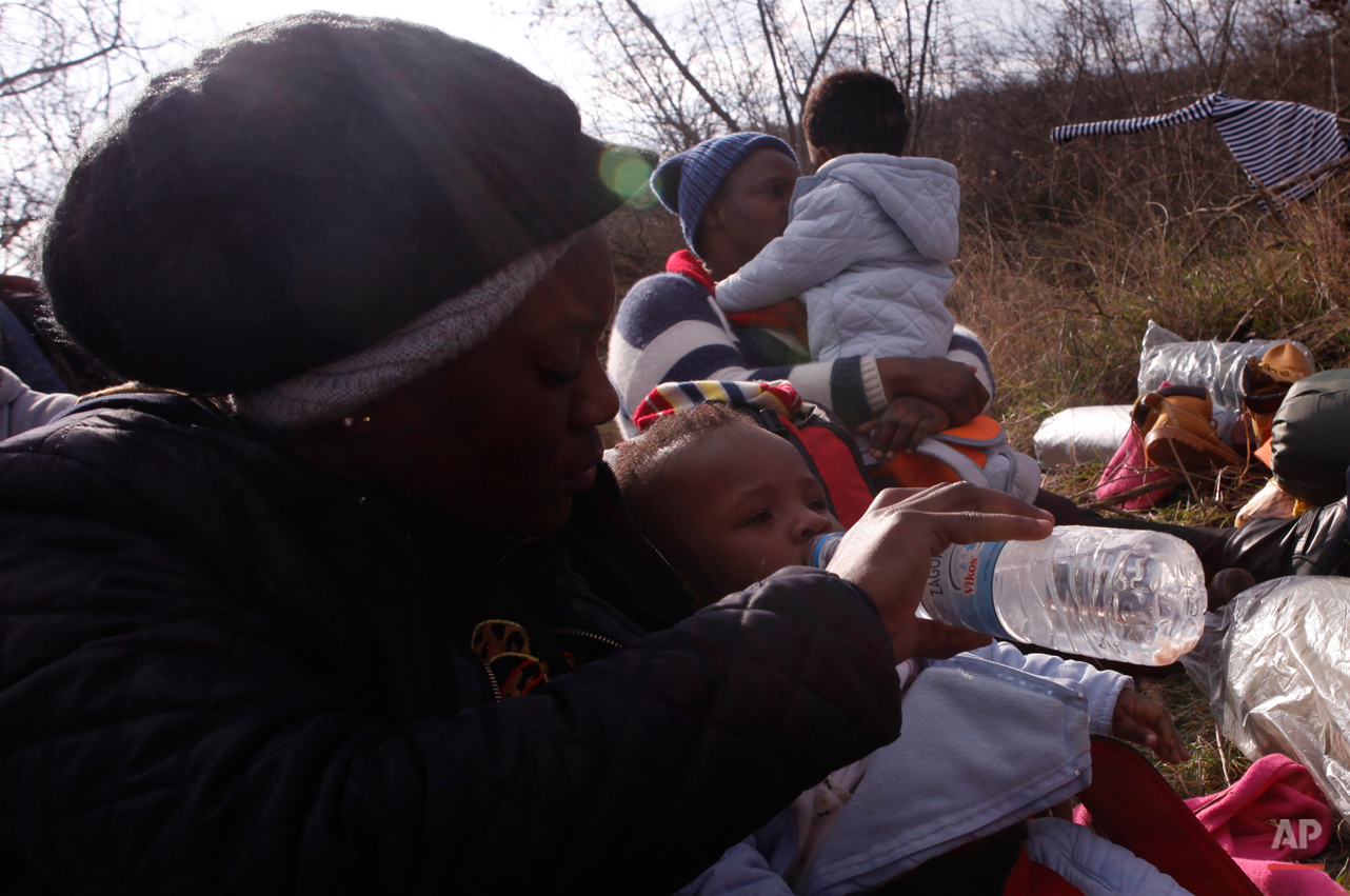  In this Saturday, Feb. 28, 2015 photo a migrant from Cameroon feeds 10-months-old Kendra Koffi on their way to the Greek-Macedonian border near the town of Polikastro, Greece.  The tide of hopeful migrants pours through the vulnerable 'back-door' co