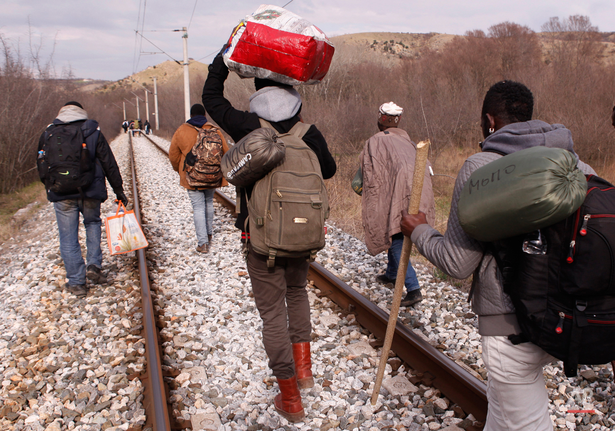  In this Saturday, Feb. 28, 2015 photo West African migrants walk on train tracks on their way to the Greek-Macedonian border near the town of Evzonoi, Greece.  The tide of hopeful migrants pours through the vulnerable 'back-door' countries in the ho