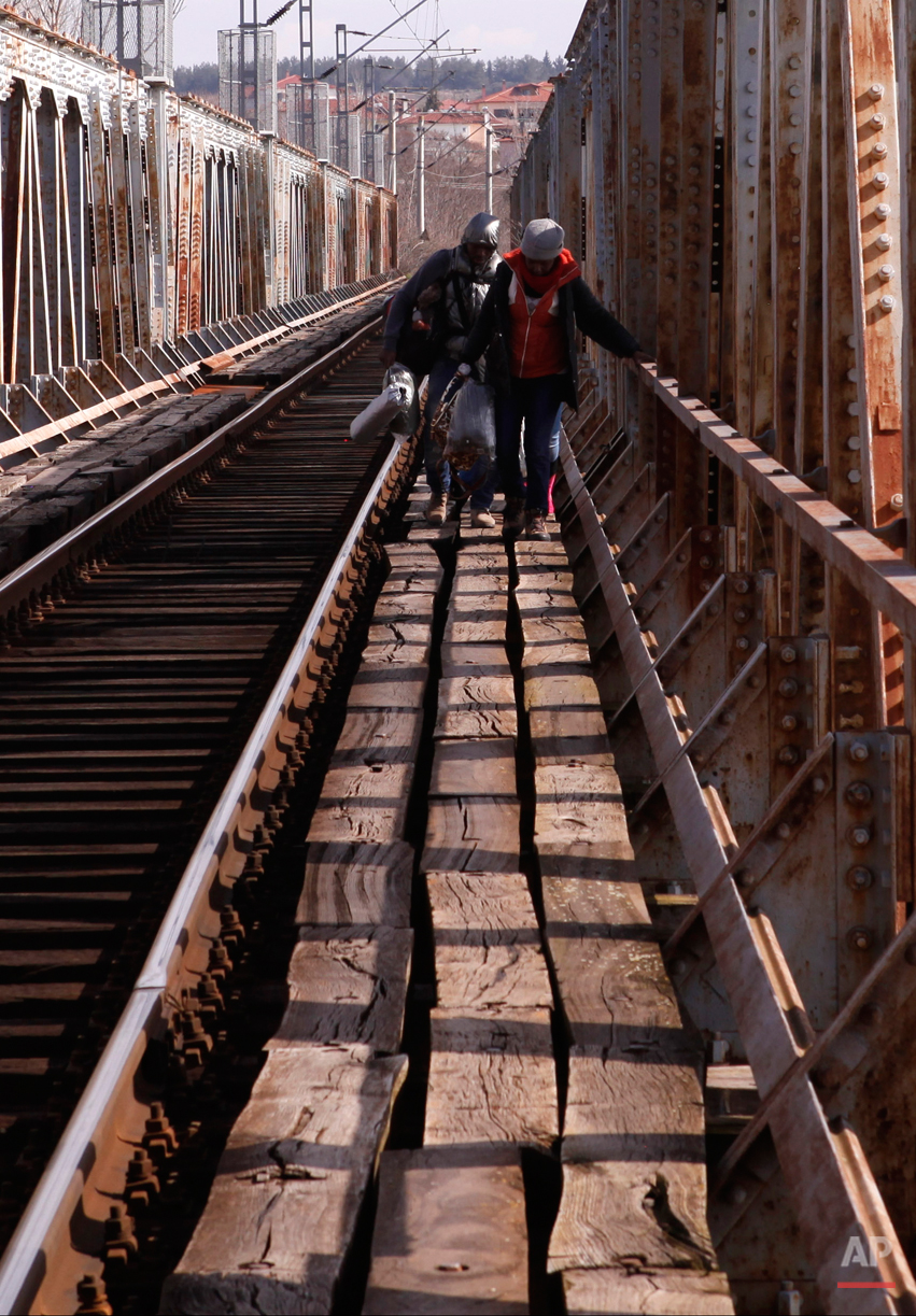  In this Saturday, Feb. 28, 2015 photo Migrants cross a railway bridge on their way to the Greek-Macedonian border near Polikastro, Greece.  The tide of hopeful migrants pours through the vulnerable 'back-door' countries in the hope of entering the 2