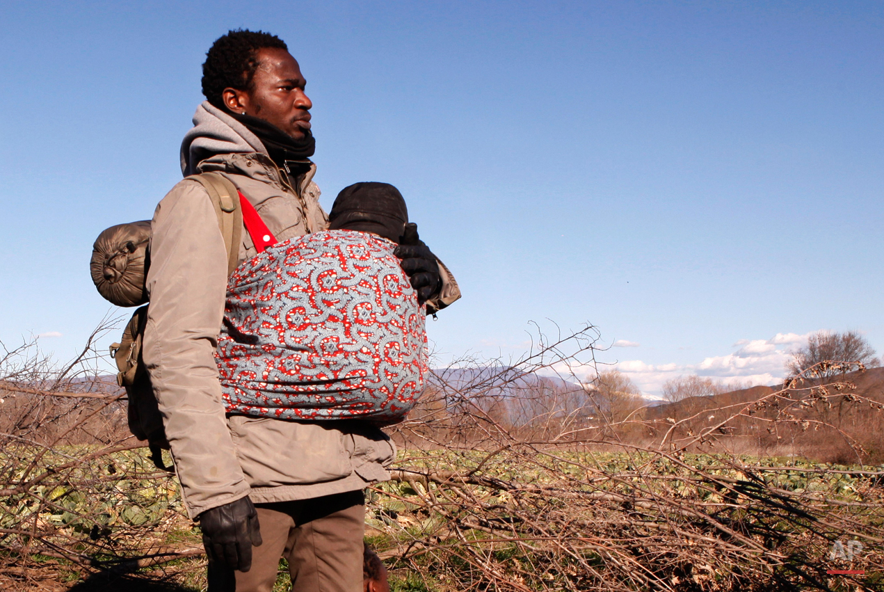  In this Tuesday, March 3, 2015 photo Jean-Paul Apetey of Ivory Coast helps carrying a baby near the village of Udovo, Macedonia.  The tide of hopeful migrants pours through the vulnerable 'back-door' countries in the hope of entering the 28-nation E