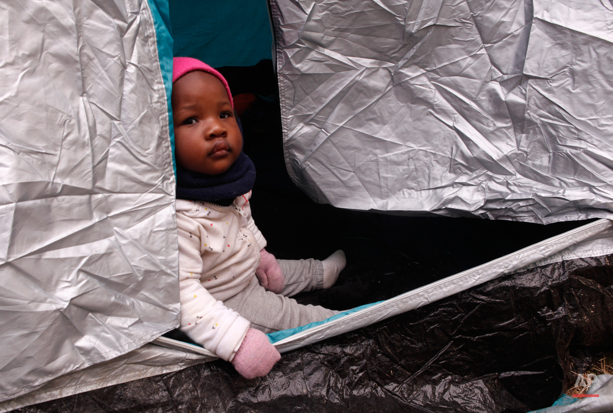  In this Monday, March 2, 2015 photo 10-months-old Kendra Koffi looks out of a tent near the town of Gevgelija, Macedonia, after crossing the border from Greece.  The tide of hopeful migrants pours through the vulnerable 'back-door' countries in the 