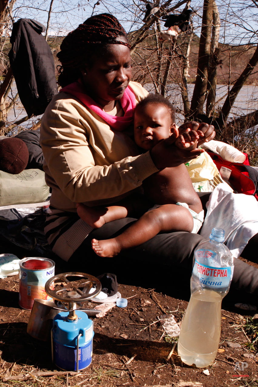  In this Tuesday, March 3, 2015 photo Sandrine Koffi washes her 10-months-old daughter Kendra with river water during a rest near the village of Marvintsi, Macedonia.  The tide of hopeful migrants pours through the vulnerable 'back-door' countries in
