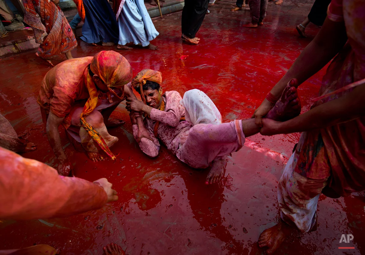 Indian Hindu men smeared with colors play holi during Lathmar festival celebrations in Nandgaon, India, Saturday, Feb. 28, 2015. During Lathmar Holi the women of Nandgaon, the hometown of Krishna, beat the men from Barsana, the legendary hometown of Radha, consort of Hindu God Krishna, with wooden sticks in response to their teasing as they depart the town. (AP Photo/Saurabh Das)
