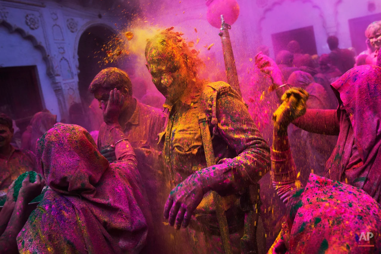 Hindu widows throw colored powder on an Indian policeman as they celebrate Holi, the Hindu festival of colors, at the Meera Sahabhagini Widow Ashram in Vrindavan, India, Tuesday, March 3, 2015. The widows, many of whom at times have lived desperate lives in the streets of the temple town, celebrated the Hindu festival of colors at the ashram. (AP Photo/Bernat Armangue)