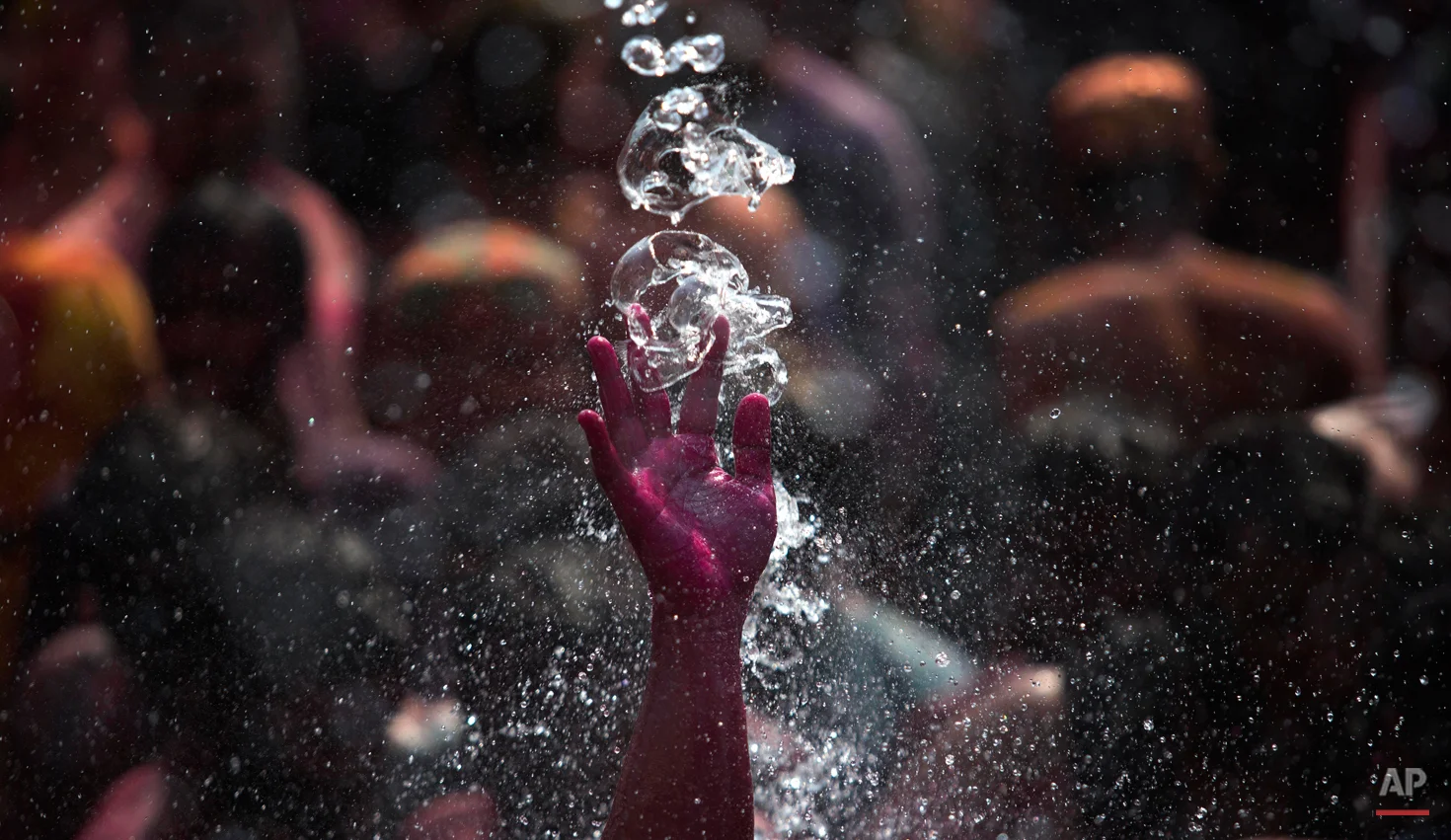 In this Friday, March 6, 2015, file photo, water falls on the colored hand of a man, dancing during Holi celebrations in Gauhati, India. Holi, the Hindu festival of colors, also marks the advent of spring. (AP Photo/Anupam Nath)