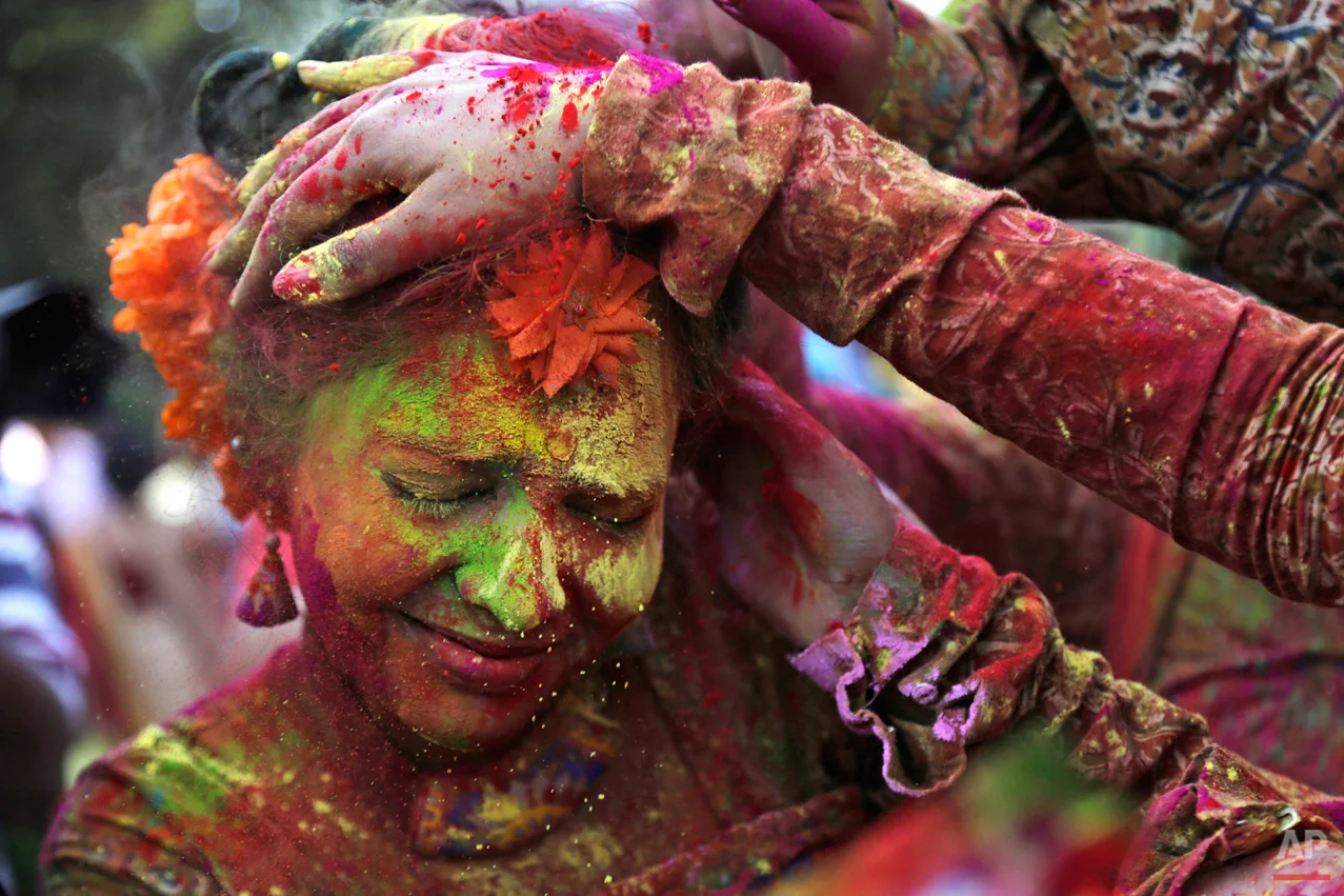 In this Thursday, March 5, 2015 photo, people smear colored powder on the face of a girl as they celebrate Holi in Kolkata, India. (AP Photo/Bikas Das)