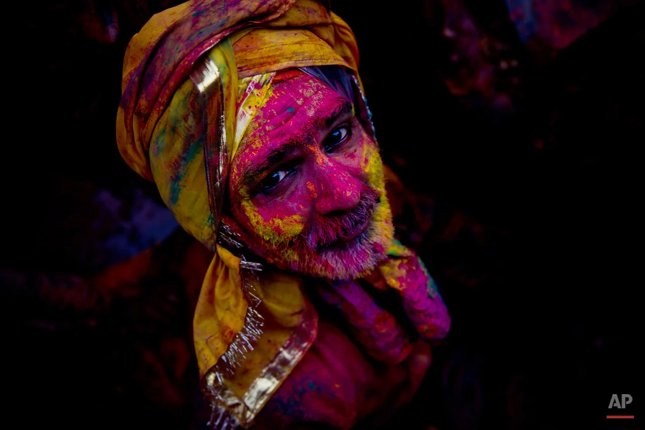 A Hindu devotee smeared with colors watches as he visits the Nandagram temple, famous for Lord Krishna and his brother Balram, during Lathmar holi festival, in Nandgaon, India, Saturday, Feb. 28, 2015. During Lathmar Holi the women of Nandgaon, the hometown of Krishna, beat the men from Barsana, the legendary hometown of Radha, consort of Hindu God Krishna, with wooden sticks in response to their teasing as they depart the town. (AP Photo/Saurabh Das)