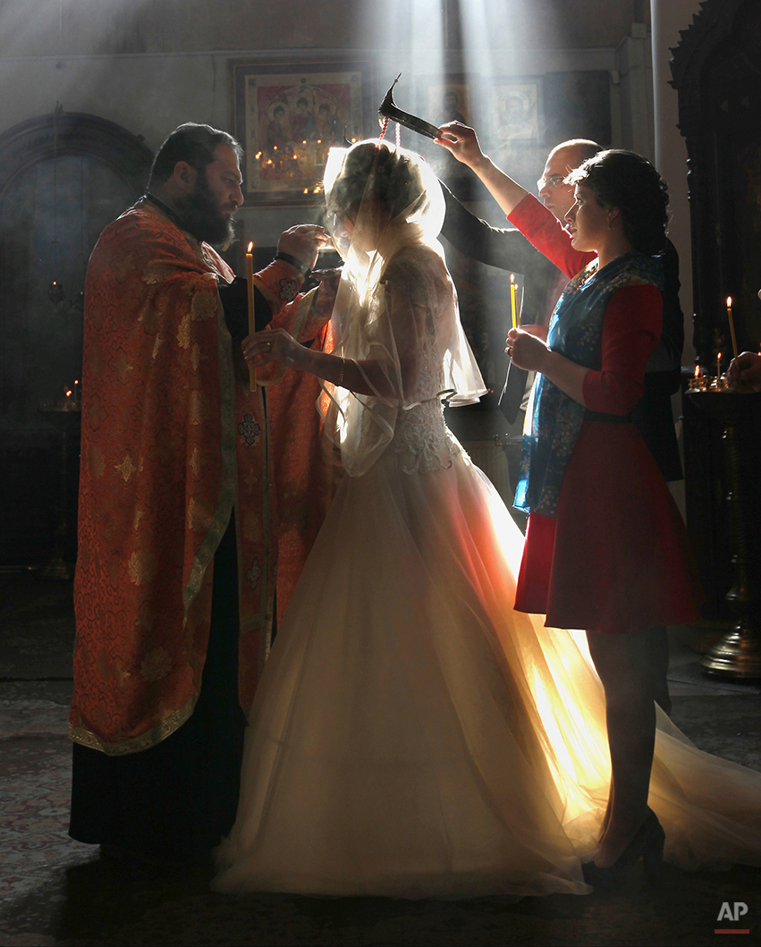  In this photo taken Saturday, Jan. 31, 2015, a Georgian Orthodox clergyman blesses newly weds during a religious ceremony at an Orthodox cathedral in Tbilisi, Georgia. (AP Photo/Shakh Aivazov) 