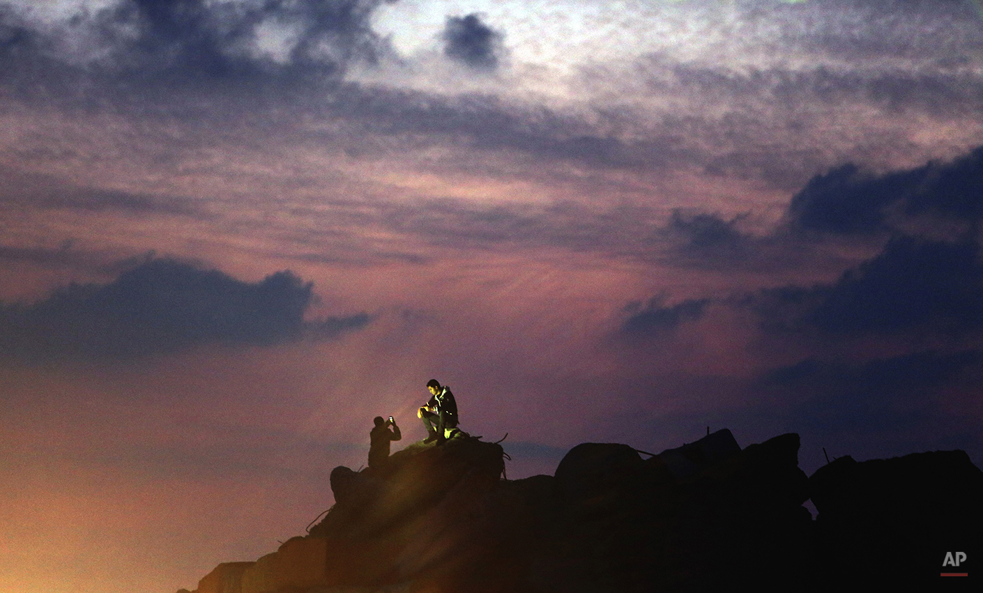  Palestinians take photos of each other as the sun sets over the water of the Mediterranean Sea at fisherman's port in Gaza City, northern Gaza Strip, Monday, Feb. 16, 2015. (AP Photo/Adel Hana) 