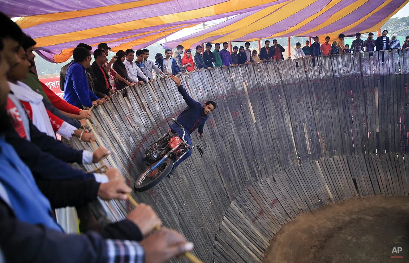 Bangladeshi daredevil S.M. Rashed performs inside a Well of Death at a trade fair in Dhaka, Bangladesh, Friday, Jan. 30, 2015. In the Well of Death, stunt drivers on motorbikes and cars drive in circles around the vertical walls of the well-shaped construction. (AP Photo/ A.M. Ahad)