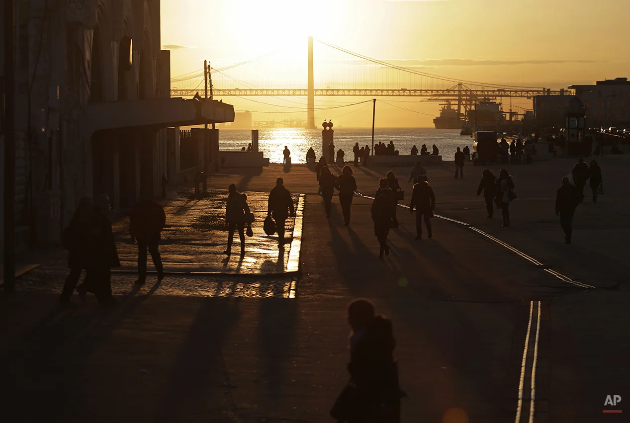 People walk to take a ferry at the Terreiro do Paco terminal port, in Lisbon, Monday, Feb. 9, 2015. Every working day during the week thousands of commuters cross and back the Tagus river by ferry to reach their jobs in the Portuguese capital. (AP Photo/Francisco Seco)