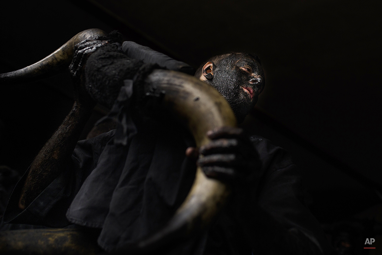  A man, covered in oil and soot carries bull horns representing the devil as he gets ready to participate during a traditional carnival celebration in the small village of Luzon, Spain, Saturday, Feb. 14, 2015. Preserved records from the 14th century