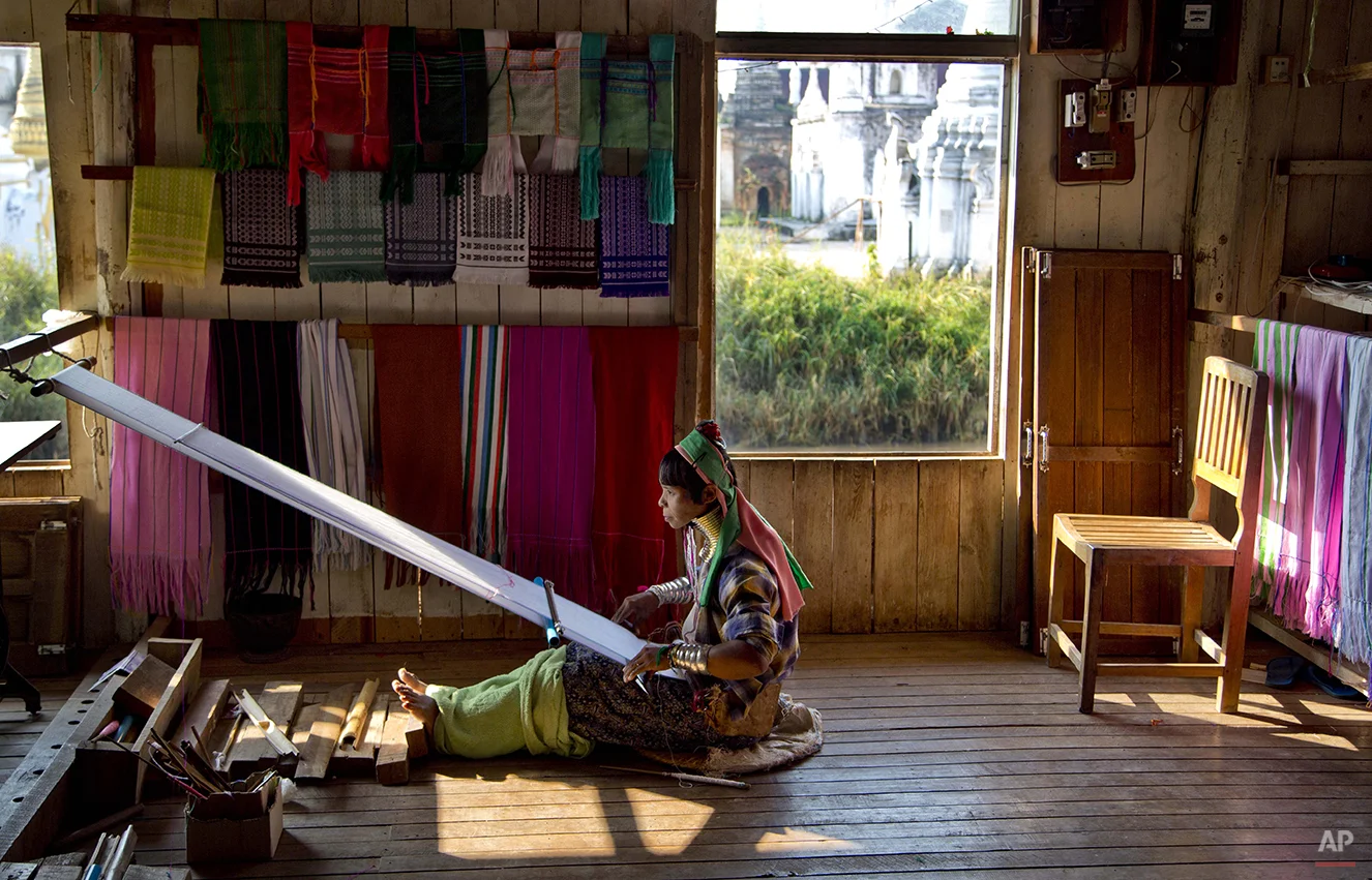 An ethnic Kayan-Padaung woman in traditional attire weaves at a souvenir shop in Ywama village, Inle Lake, northeastern Shan state, Myanmar, Monday, Feb. 16, 2015. Wearing neck-rings is officially discouraged in Myanmar but shop owners employ Padang women in traditional attire as a tourist attraction. (AP Photo/Gemunu Amarasinghe)
