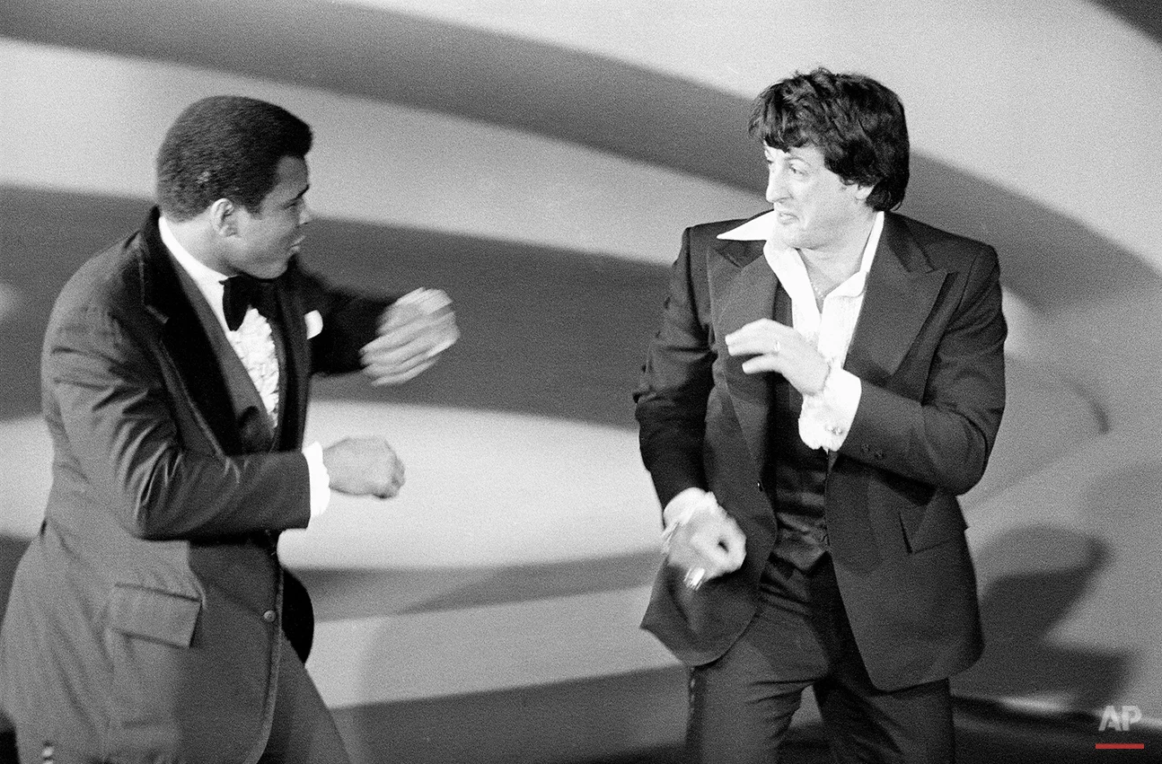 Heavyweight champion Muhammad Ali, left, makes a suprise appearance on the Academy Awards show, staging a sparring with Sylvester Stallone, actor and screenwriter of the boxing drama "Rocky," on March 28, 1977, in Los Angeles, California. (AP Photo)