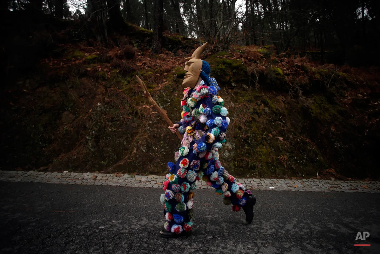 In this photo taken on Sunday, Feb. 15, 2015 a man dressed in local Carnival traditional costume runs as he parades with others during Carnival festivities in Lazarim, northeastern Portugal. While Rio de Janeiro may boast the worldís most famous carnival, the festive period of masquerades and wild and colorful costumes that precedes the Christian religious season of Lent is also a permanent and popular fixture for celebration in Spain and Portugal, with each country having its own strange and unique way of doing it. Portugalís most famous carnival takes place in the north-central town of Lazarin, with its pagan ëcaretoí ritual of masked young men dressed in colored woolen quilts and donning brass, leather or wooden masks as they dance and chase local people _ especially young women _ through the streets, trying to scare them by making lots of noise and jingling bells on their backs. (AP Photo/Francisco Seco)