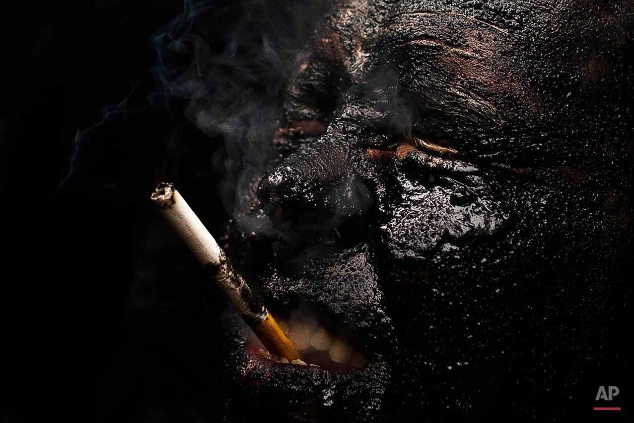 In this photo taken on Saturday, Feb. 14, 2015 a man, covered in oil and soot representing the devil, smokes a cigarette as he gets ready for the carnaval in the small village of Luzon, Spain. While Rio de Janeiro may boast the worldís most famous carnival, the festive period of masquerades and wild and colorful costumes that precedes the Christian religious season of Lent is also a permanent and popular fixture for celebration in Spain and Portugal, with each country having its own strange and unique way of doing it. In Spainís central town of Luzon, men covered in oil and soot wear bull horns and cowbells to represent the devil. Records of Luzonís carnival date as far back as the 14th century although it is believed to be much older. (AP Photo/Andres Kudacki)
