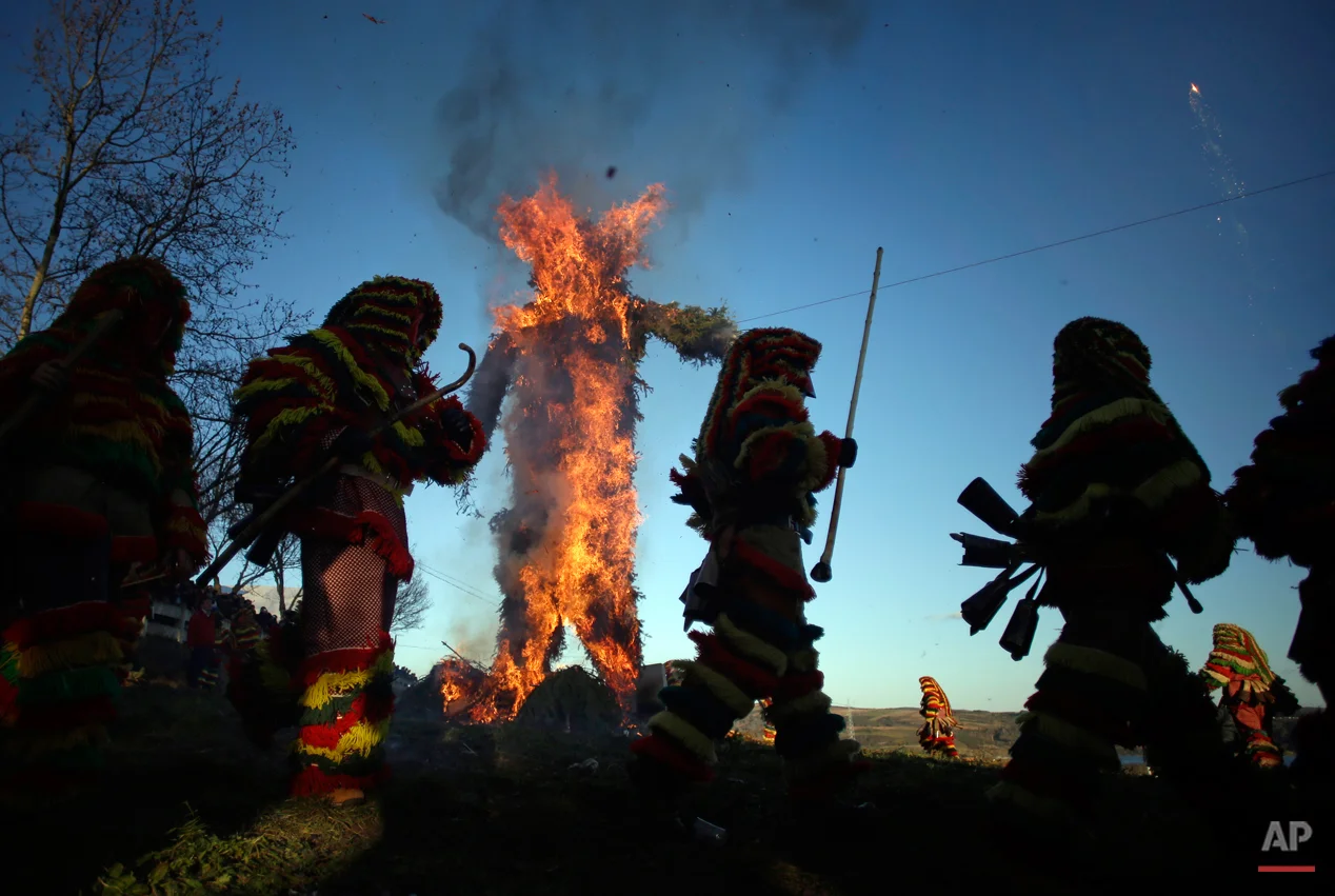 In this photo taken on Tuesday, Feb. 17, 2015 revellers dressed in traditional costumes run around a burning effigy of a traditional figure during annual Carnival festivities, in Podence, northeastern Portugal. While Rio de Janeiro may boast the worldís most famous carnival, the festive period of masquerades and wild and colorful costumes that precedes the Christian religious season of Lent is also a permanent and popular fixture for celebration in Spain and Portugal, with each country having its own strange and unique way of doing it. Portugalís most famous carnival takes place in the north-central town of Lazarin, with its pagan ëcaretoí ritual of masked young men dressed in colored woolen quilts and donning brass, leather or wooden masks as they dance and chase local people _ especially young women _ through the streets, trying to scare them by making lots of noise and jingling bells on their backs. (AP Photo/Francisco Seco)