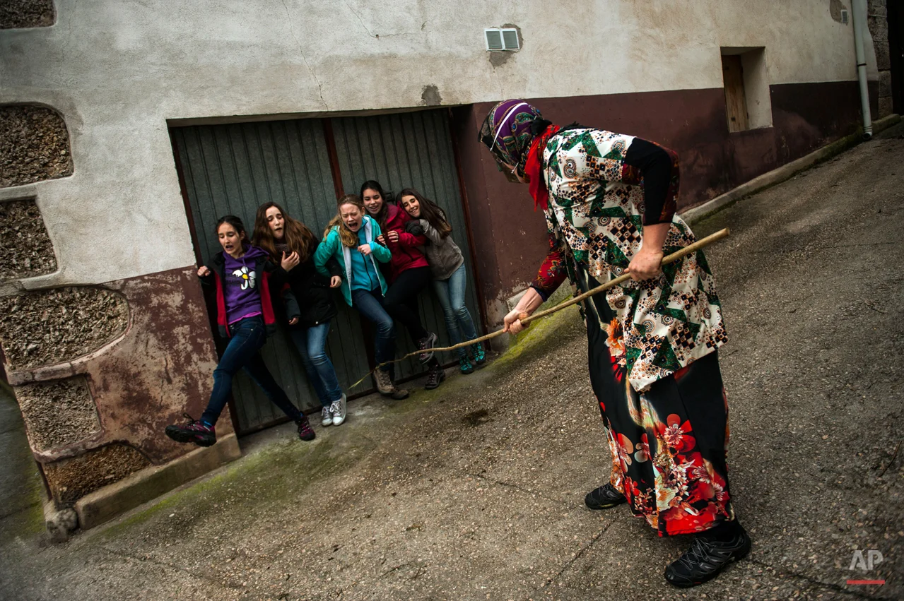 In this photo taken on Sunday, Feb. 15, 2015 a group of young girls react next to a ''Mamuxarro'' during the carnival, in the small town of Unanu, northern Spain, While Rio de Janeiro may boast the worldís most famous carnival, the festive period of masquerades and wild and colorful costumes that precedes the Christian religious season of Lent is also a permanent and popular fixture for celebration in Spain and Portugal, with each country having its own strange and unique way of doing it. In the northern Spanish ancient village of Unamu, people dress up as 'Mamuxarroí, folkloric figures in white with a red sash and a metal mask to cover their faces as they pursue townsfolk with sticks. According to custom, their 'victims' (usually young women) must kneel and kiss the mamuxarroís knee after he makes the sign of the cross on their forehead. (AP Photo/Alvaro Barrientos)