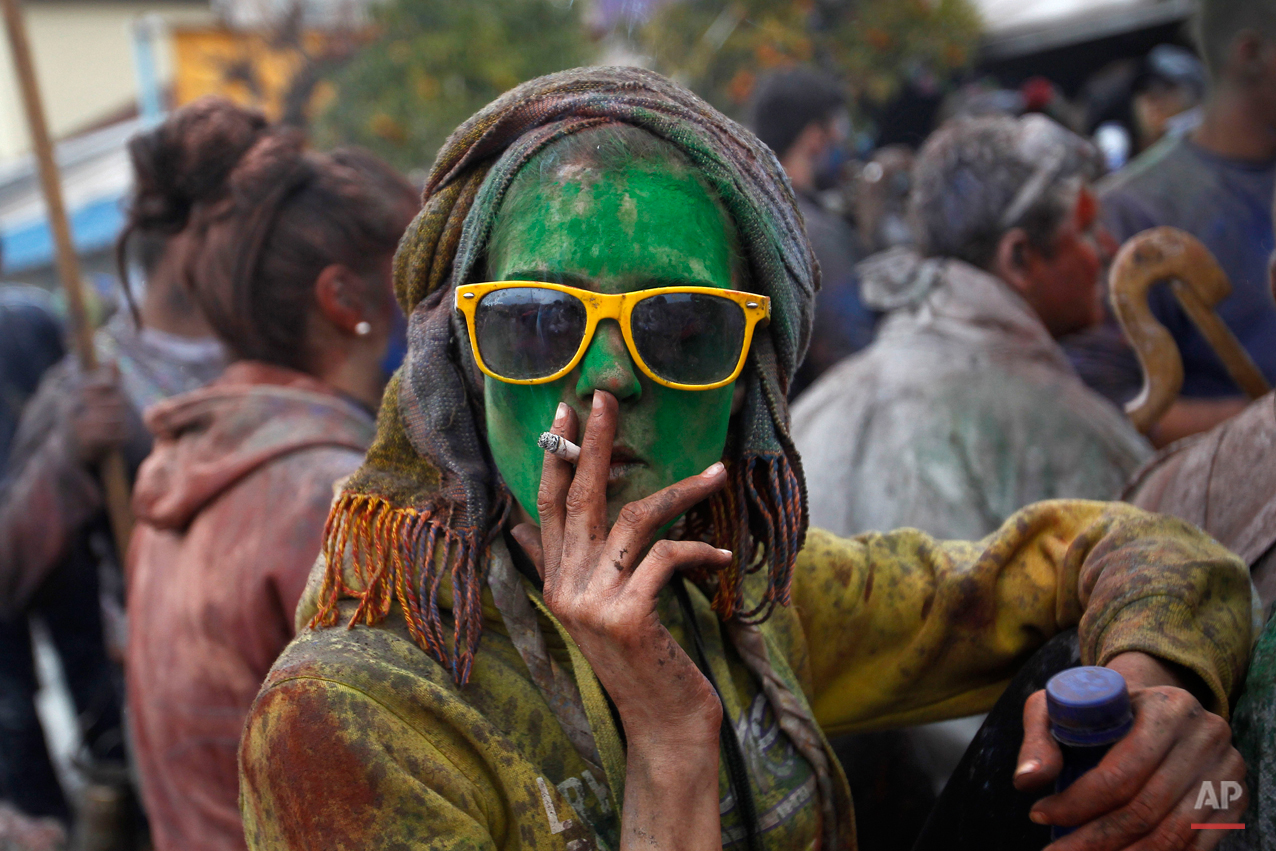  A local reveler smokes a cigarette as she celebrate Clean Monday with a flour war, a unique colorful flour fight marking the end of the carnival season in the port town of Galaxidi, some 200 kilometers (120 miles) west of Athens, Monday, Feb. 23, 20