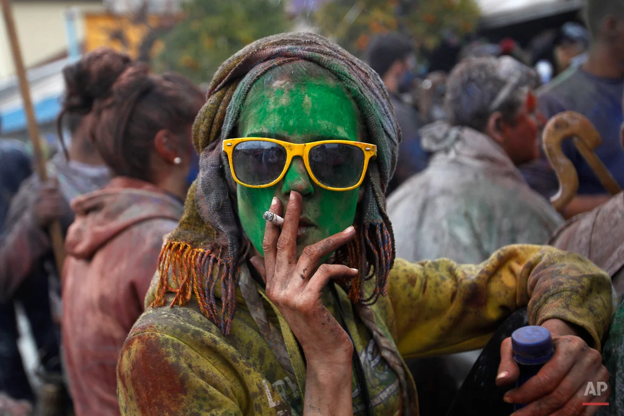 A local reveler smokes a cigarette as she celebrate Clean Monday with a flour war, a unique colorful flour fight marking the end of the carnival season in the port town of Galaxidi, some 200 kilometers (120 miles) west of Athens, Monday, Feb. 23, 2015. The flour fight, on the coastal road lining Galaxidiís old harbor, takes place on Clean Monday, the beginning of the 40-day Christian Lent fast that ends on Easter Sunday. Although Clean Monday ceremonies abound across Greece, the most common being kite-flying, Galaxidiís flour-fight is unique, and is thought to have been influenced by similar goings-on in Sicily in the 19th century. (AP Photo/Petros Giannakouris)