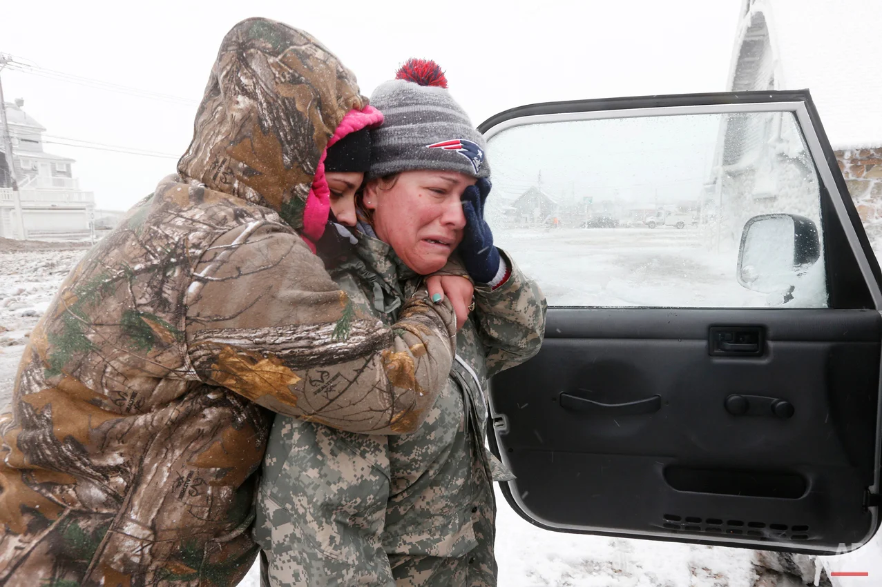 Taylor Millar, left, hugs her friend Jennifer Bruno, after Bruno was forced to vacate her house when it was heavily damaged by ocean waves in a winter storm, Tuesday, Jan. 27, 2015, in Marshfield, Mass. The storm has punched out a section of the seawall in the coastal town of Marshfield, police said. (AP Photo/Michael Dwyer)