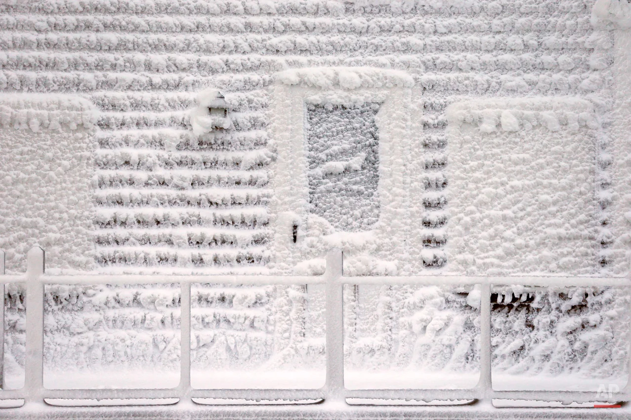 AP10ThingsToSee - Frozen sea spray from a winter storm coats a house in Scituate, Mass., Wednesday, Jan. 28, 2015. As Massachusetts continues digging out from the Blizzard of 2015, forecasters warn of a new round of storms that could dump several more inches of snow on Friday and again over the weekend. (AP Photo/Michael Dwyer)