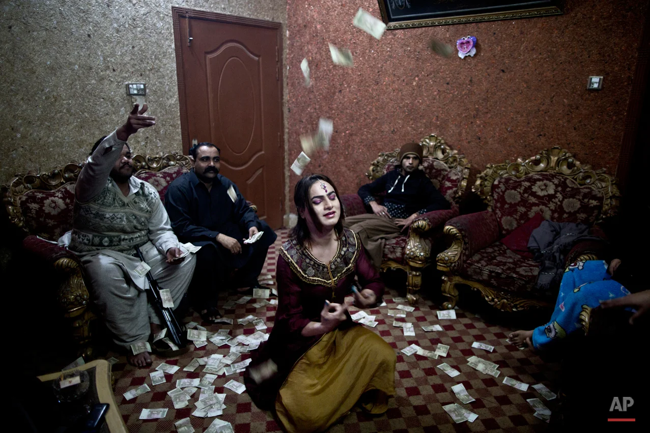 In this Thursday, Jan. 15, 2015 photo, Pakistani Waseem Akram, 27, dances during a private party in Rawalpindi, Pakistan. By day, Akram sells mobile phone accessories from an alleyway shop in an old neighborhood of this Pakistani city. But by night, he stands before a mirror, shaving away his beard and picking through mascara and rouge to become Rani, a female wedding party dancer. ìBeing a dancer at weddings, parties and private events ... helps me earn much more money than working in a shop,î Akram said. (AP Photo/Muhammed Muheisen)