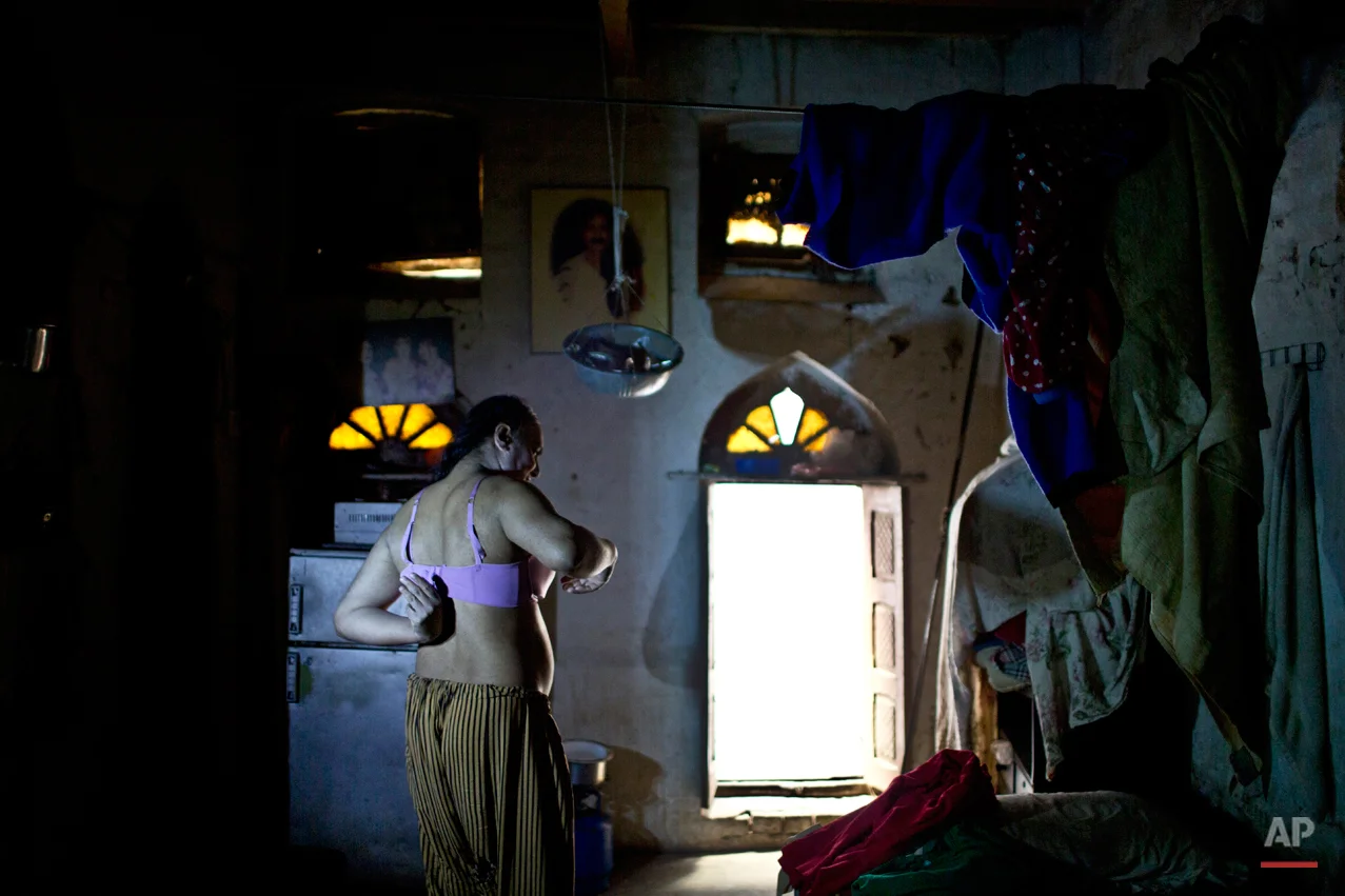 In this Thursday, Jan. 8, 2015 photo, Pakistani Bakhtawar Ijaz, 43, wears a bra under the light of a lamp due to a power cut, while preparing himself to go out, at his home in Rawalpindi, Pakistan. Across conservative Pakistan, where Islamic extremists launch near-daily attacks and many follow a strict interpretation of their Muslim faith, male cross-dressers like Ijaz face a challenge of balancing two identities. Some left their villages for the anonymity of a big city, fearing the reactions of their families while still concealing their identity from neighbors and co-workers. (AP Photo/Muhammed Muheisen)