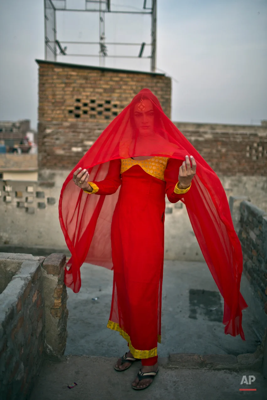 In this Saturday, Jan. 10, 2015 photo, Pakistani Waseem Akram, 27, poses for a picture at the rooftop of a friend's place in Rawalpindi, Pakistan. By day, 27-year-old Waseem Akram sells mobile phone accessories from an alleyway shop in an old neighborhood of this Pakistani city. But by night, Akram stands before a mirror, shaving away his beard and picking through mascara and rouge to become Rani, a female wedding party dancer. (AP Photo/Muhammed Muheisen)