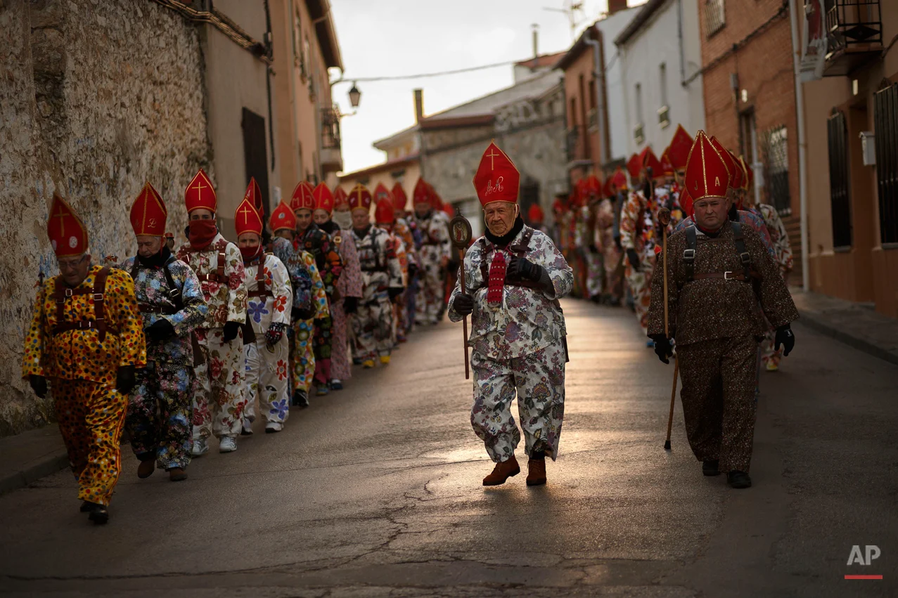 Aniceto Rodrigo, 78, Diablo Mayor or 'greater devil', center, leads the 'Endiablada' traditional festival in Almonacid Del Marquesado, Spain, Tuesday, Feb. 3, 2015. The "Endiablada" (The Brotherhood of the Devils) festivals are celebrated each Feb. 2-3 in the central Spanish town of Almonacid del Marquesado since medieval times or before. In the festival, men from the town dress up as devil-type characters in colorful jumpsuit costumes and red miter hats. They don large heavy copper cowbells around their waists, which clang incessantly as they walk, dance and jump through the town's winding streets and visit the cemetery. The Feb. 3 day procession commemorates the day of Saint Blas. According to a local legend, town shepherds found a statue of the saint and then won a competition with folk from a nearby town to keep the effigy and rang the bells of their animals in celebration. (AP Photo/Daniel Ochoa de Olza)