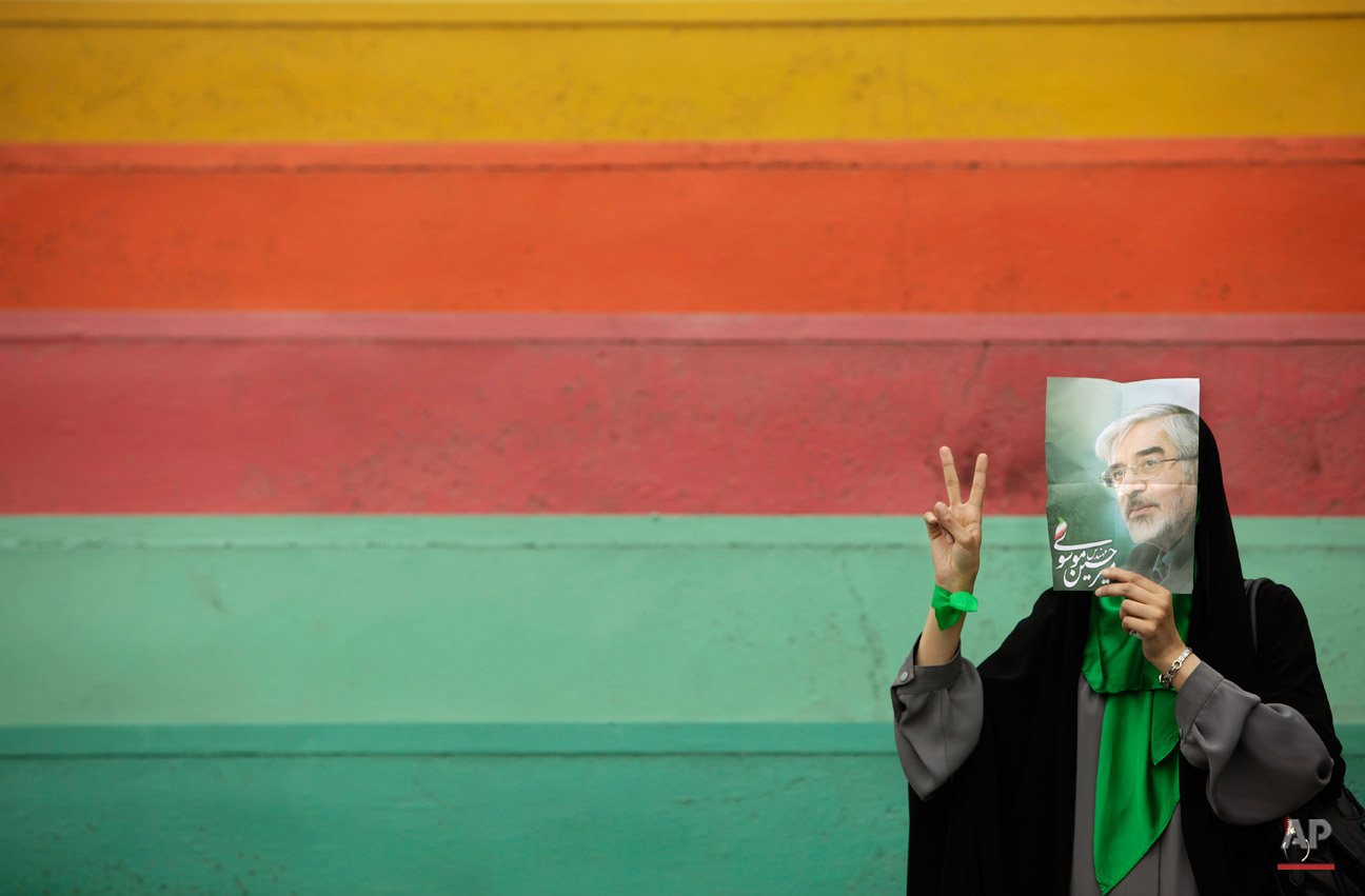  A supporter of main challenger and reformist candidate Mir Hossein Mousavi, not wanting to be photographed, hides her face using a poster of him as she waits in the stands at an election rally at the Heidarnia stadium in Tehran, Iran, Tuesday, June 