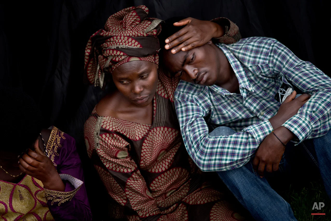 Bizimana Emmanuel, who was born two years before the genocide, is consoled by an unidentified woman while attending a public ceremony to mark the 20th anniversary of the Rwandan genocide, at Amahoro stadium in Kigali, Rwanda Monday, April 7, 2014. Sorrowful wails and uncontrollable sobs resounded Monday as thousands of Rwandans packed the country's main sports stadium to mark the 20th anniversary of the beginning of a devastating 100-day genocide. (AP Photo/Ben Curtis)